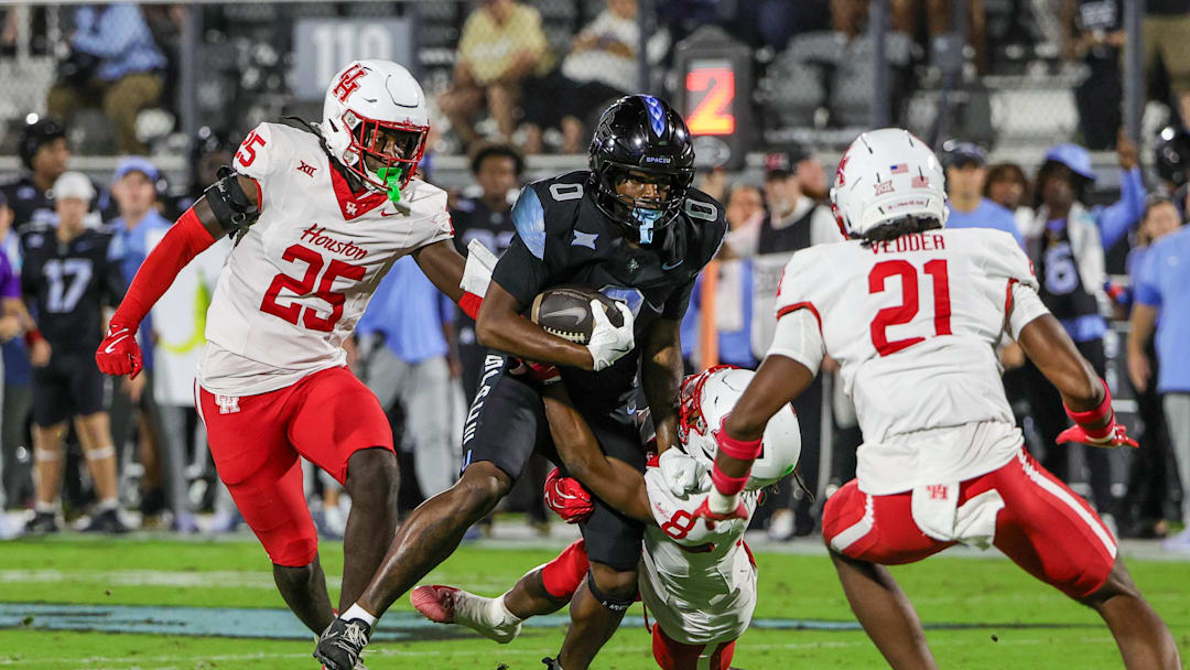 Nov 7, 2025; Orlando, Florida, USA; UCF Knights tight end Dylan Wade (0) is tackled by Houston Cougars defensive back Kentrell Webb (8) during the first quarter at Acrisure Bounce House. Mandatory Credit: Mike Watters-Imagn Images
