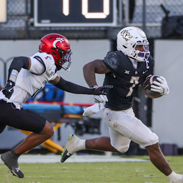 Oct 12, 2024; Orlando, Florida, USA; UCF Knights running back RJ Harvey (7) runs the ball as Cincinnati Bearcats defensive back Logan Wilson (13) moves in during the second half at FBC Mortgage Stadium. Mandatory Credit: Mike Watters-Imagn Images
