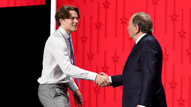 Hockey player shakes hands with the NHL commissioner 