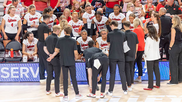 Nebraska coaches and players gather on the sideline during the AVCA First Serve.