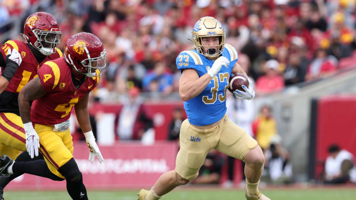 Nov 18, 2023; Los Angeles, California, USA; UCLA Bruins running back Carson Steele (33) runs past USC Trojans safety Max Williams (4) during the first quarter at United Airlines Field at Los Angeles Memorial Coliseum. Mandatory Credit: Jason Parkhurst-USA TODAY Sports