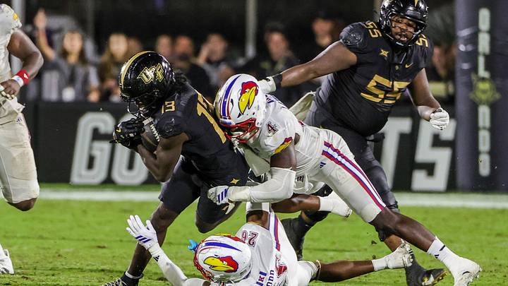 Oct 4, 2025; Orlando, Florida, USA; UCF Knights wide receiver Chris Domercant (13) is tackled by Kansas Jayhawks linebacker Trey Lathan (4) during the second half at FBC Mortgage Stadium. Mandatory Credit: Mike Watters-Imagn Images