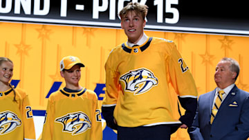 Nashville Predators draft pick Matthew Wood puts on his sweater after being selected with the 15th pick in the first round of the NHL draft at Bridgestone Arena in Nashville, Tenn., on June 28, 2023.