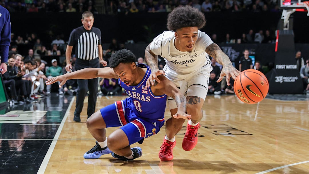 Jan 5, 2025; Orlando, Florida, USA; UCF Knights guard Mikey Williams (1) and Kansas Jayhawks guard David Coit (8) chase a loose ball during the second half at Addition Financial Arena. Mandatory Credit: Mike Watters-Imagn Images