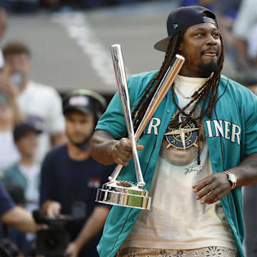 Jul 10, 2023; Seattle, Washington, USA; Former Seattle Seahawks running back Marshawn Lynch brings the championship trophy to the field before the finals of the All-Star Home Run Derby at T-Mobile Park.  Mandatory Credit: Joe Nicholson-Imagn Images