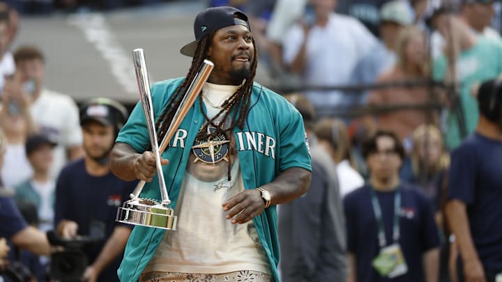 Jul 10, 2023; Seattle, Washington, USA; Former Seattle Seahawks running back Marshawn Lynch brings the championship trophy to the field before the finals of the All-Star Home Run Derby at T-Mobile Park.  Mandatory Credit: Joe Nicholson-Imagn Images