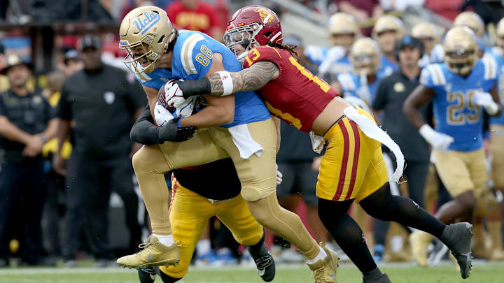 Nov 18, 2023; Los Angeles, California, USA; USC Trojans linebacker Mason Cobb (13) tackles UCLA Bruins tight end Moliki Matavao (88) during the first quarter at United Airlines Field at Los Angeles Memorial Coliseum. Mandatory Credit: Jason Parkhurst-Imagn Images