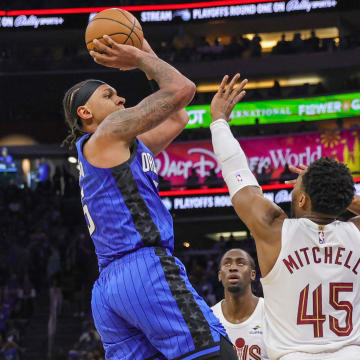 Apr 25, 2024; Orlando, Florida, USA; Orlando Magic forward Paolo Banchero (5) shoots the ball against Cleveland Cavaliers guard Donovan Mitchell (45) during the second quarter of game three of the first round for the 2024 NBA playoffs at Kia Center.