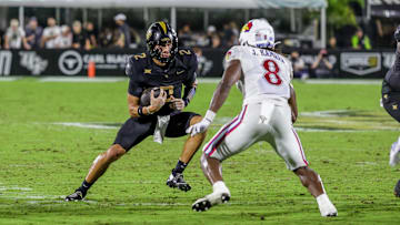 Oct 4, 2025; Orlando, Florida, USA; UCF Knights quarterback Tayven Jackson (2) runs the ball in front of Kansas Jayhawks linebacker Jon Jon Kamara (8) during the second quarter at FBC Mortgage Stadium. Mandatory Credit: Mike Watters-Imagn Images