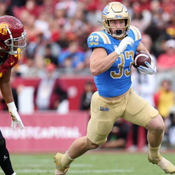 Nov 18, 2023; Los Angeles, California, USA; UCLA Bruins running back Carson Steele (33) runs past USC Trojans safety Max Williams (4) during the first quarter at United Airlines Field at Los Angeles Memorial Coliseum. Mandatory Credit: Jason Parkhurst-USA TODAY Sports