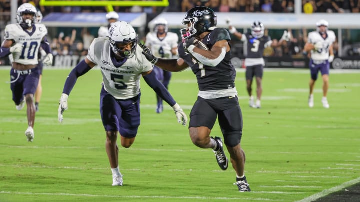 Aug 29, 2024; Orlando, Florida, USA; UCF Knights running back RJ Harvey (7) runs the ball against New Hampshire Wildcats defensive back Wande Owens (5) during the second quarter at FBC Mortgage Stadium. Mandatory Credit: Mike Watters-USA TODAY Sports