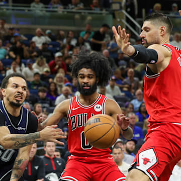 Apr 7, 2024; Orlando, Florida, USA; Orlando Magic guard Cole Anthony (50) passes the ball around Chicago Bulls guard Coby White (0) and center Nikola Vucevic (9) during the second quarter at KIA Center. Mandatory Credit: Mike Watters-Imagn Images