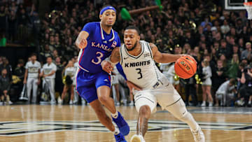 Jan 10, 2024; Orlando, Florida, USA; UCF Knights guard Darius Johnson (3) drives around Kansas Jayhawks guard Dajuan Harris Jr. (3) during the second half at Addition Financial Arena. Mandatory Credit: Mike Watters-Imagn Images