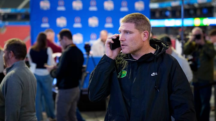 Oregon defensive coordinator Tosh Lupoi talks on the phone as Indiana speaks during a media day as the Oregon Ducks arrive on Jan. 7, 2025, in Atlanta, Georgia ahead of the Peach Bowl at Mercedes-Benz Stadium.