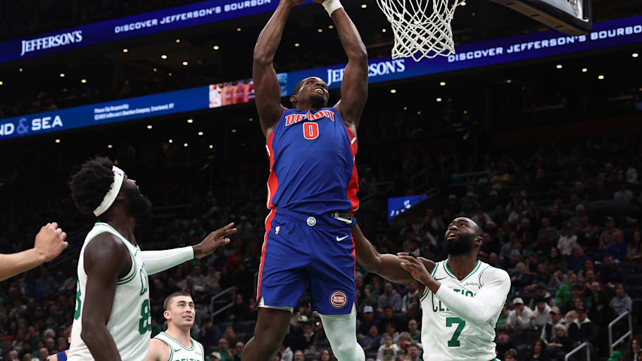 Pistons center Jalen Duren goes in to dunk as Celtics guard Jaylen Brown looks on.