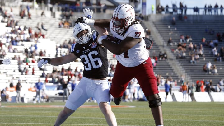 Dec 23, 2023; Birmingham, AL, USA; Troy Trojans offensive linemen Derrick Graham (77) runs after a catch for a touchdown as Duke Blue Devils linebacker Nick Morris Jr. (36) attempts to make the stop during the second half at Protective Stadium.