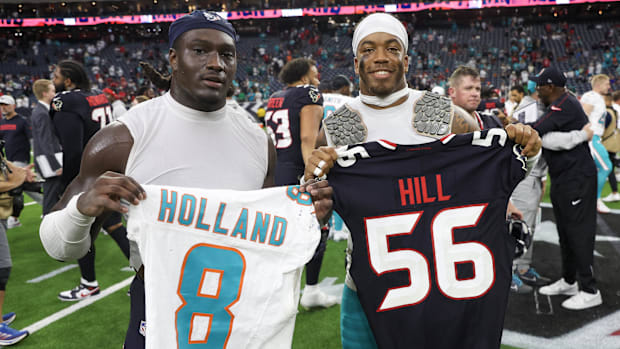 Houston Texans linebacker Jamal Hill (56) (left ) and Miami Dolphins safety Jevon Holland (8) exchange jerseys