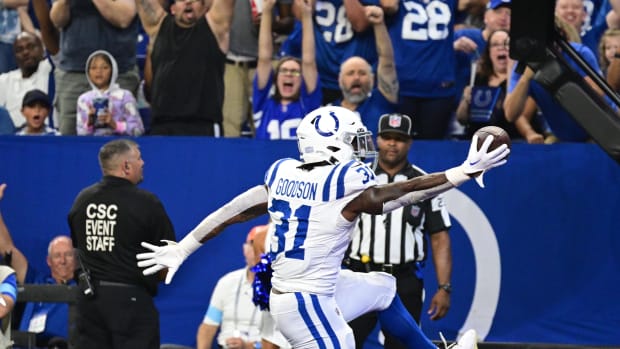 Colts running back Tyler Goodson (all-white uniform with blue trim) celebrates with fans after scoring a touchdown. 