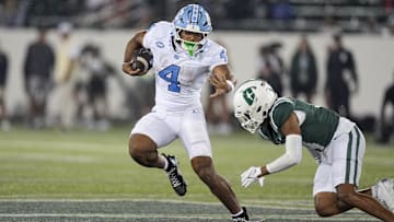 Sep 6, 2025; Charlotte, North Carolina, USA;  North Carolina Tar Heels running back Caleb Hood (4) tries to avoid Charlotte 49ers defensive back Gavin Shipman (4) during the second half at Jerry Richardson Stadium. Mandatory Credit: Jim Dedmon-Imagn Images