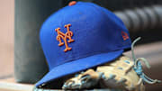 Jul 13, 2022; Atlanta, Georgia, USA; A detailed view of a New York Mets hat and glove in the dugout against the Atlanta Braves in the eighth inning at Truist Park. 