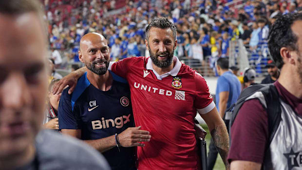 Chelsea assistant coach Willy Caballero walks off the field with Wrexham forward Ollie Palmer (9) after the match.