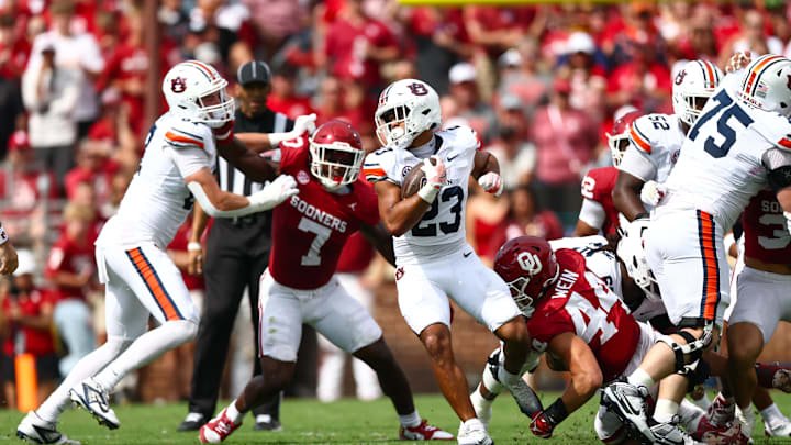 Sep 20, 2025; Norman, Oklahoma, USA;  Auburn Tigers running back Jeremiah Cobb (23) runs with the ball as Oklahoma Sooners defensive lineman Taylor Wein (44) and Oklahoma Sooners linebacker Sammy Omosigho (7) defend during the first half at Gaylord Family-Oklahoma Memorial Stadium. Mandatory Credit: Kevin Jairaj-Imagn Images