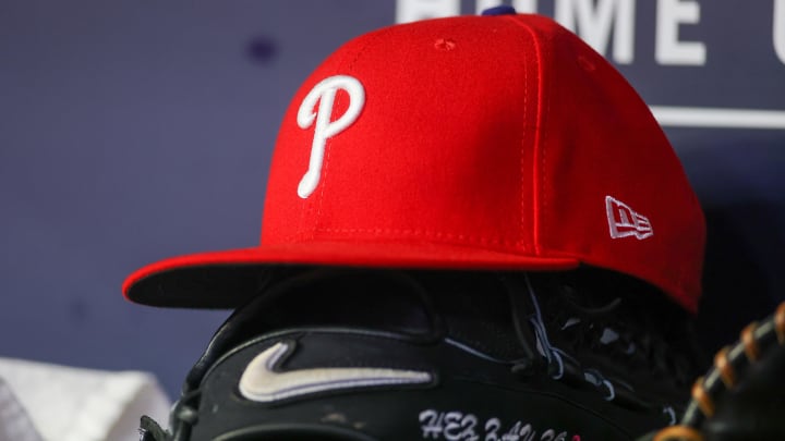A detailed view of a Philadelphia Phillies hat and glove on the bench