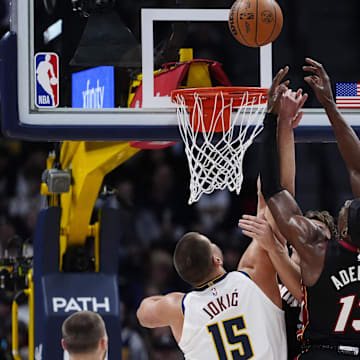 Nov 5, 2025; Denver, Colorado, USA; Miami Heat center Bam Adebayo (13) and Denver Nuggets center Nikola Jokic (15) reach for the rebound in the first quarter at Ball Arena. Mandatory Credit: Ron Chenoy-Imagn Images