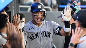 Jul 23, 2025; Toronto, Ontario, CAN;  New York Yankees designated hitter Aaron Judge (99) celebrates with team mates in the dugout after hitting a two run home run against the Toronto Blue Jays in the sixth inning at Rogers Centre. Mandatory Credit: Dan Hamilton-Imagn Images