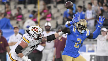 Oct 12, 2024; Pasadena, California, USA; UCLA Bruins linebacker Oluwafemi Oladejo (2) tries to knock down a pass by Minnesota Golden Gophers quarterback Max Brosmer (not pictured) during the first quarter at Rose Bowl. LBlocking at left is Minnesota Golden Gophers offensive lineman Quinn Carroll (77). Mandatory Credit: Robert Hanashiro-Imagn Images
