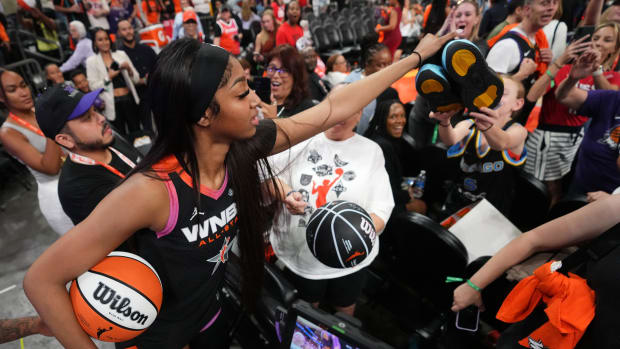 Team WNBA forward Angel Reese hands off her shoes to a young fan after the WNBA All-Star Game.