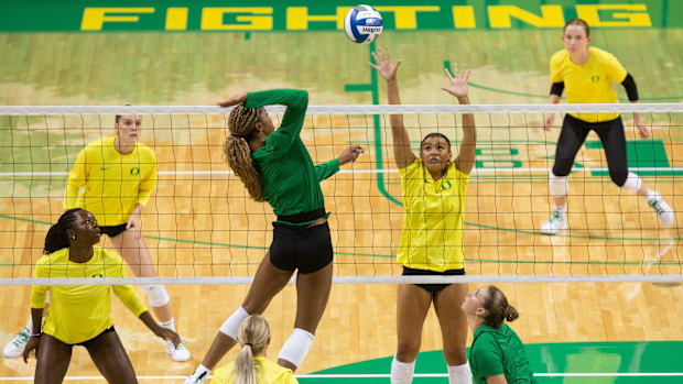 niversity of Oregon volleyball player Onye Ofoegbu, center, goes up for a shot against her teammates