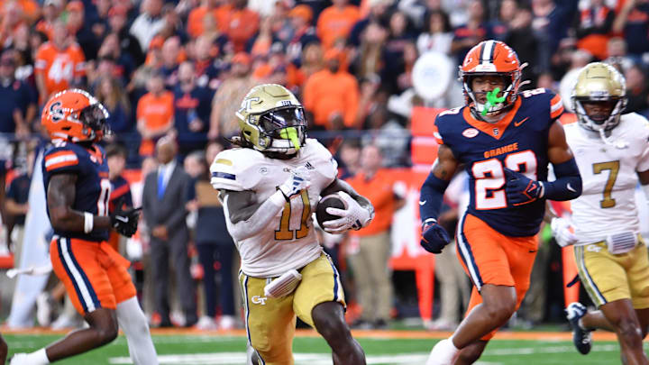 Sep 7, 2024; Syracuse, New York, USA; Georgia Tech Yellow Jackets running back Jamal Haynes (11) scores a touchdown ahead of Syracuse Orange defensive back Devin Grant (23) in the fourth quarter at the JMA Wireless Dome. Mandatory Credit: Mark Konezny-Imagn Images