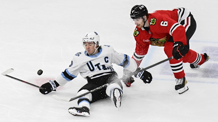 Mar 30, 2025; Chicago, Illinois, USA;  Utah Hockey Club center Clayton Keller (9) and Chicago Blackhawks defenseman Sam Rinzel (6) chase the puck during the third period at United Center. Mandatory Credit: Matt Marton-Imagn Images