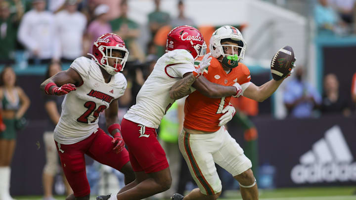 Nov 18, 2023; Miami Gardens, Florida, USA; Miami Hurricanes wide receiver Xavier Restrepo (7) is tackled short of the end zone by Louisville Cardinals defensive back Quincy Riley (3) during the fourth quarter at Hard Rock Stadium. Mandatory Credit: Sam Navarro-Imagn Images