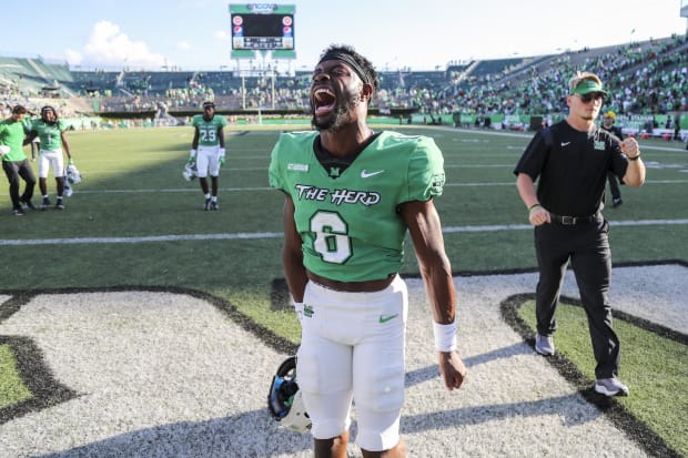 Football player Micah Abraham celebrates after a win in a green football jersey.