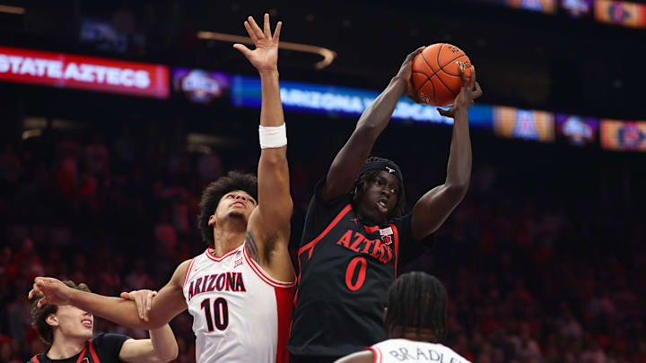 Dec 20, 2025; Phoenix, Arizona, USA; San Diego State Aztecs forward Magoon Gwath (0) grabs a rebound against Arizona Wildcats forward Koa Peat (10) during the Hall of Fame Series at Mortgage Matchup Center. Mandatory Credit: Mark J. Rebilas-Imagn Images