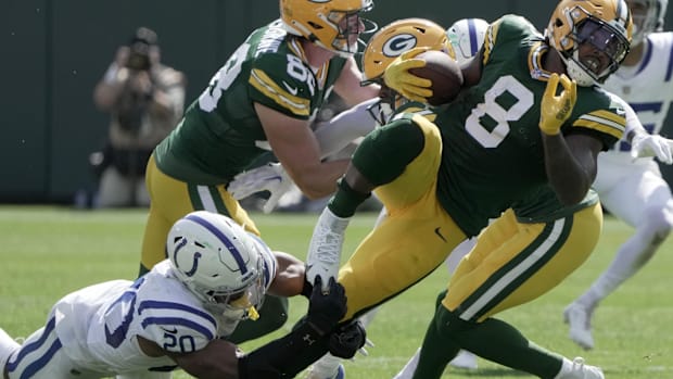 Colts safety Nick Cross (all-white uniform) makes a desperation tackle on a Packers ball-carrier (green pants/helmet). 