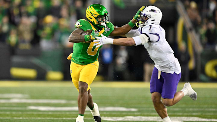 Dec 20, 2025; Eugene, OR, USA; Oregon Ducks running back Jordon Davison (0) rushes and stiff arms James Madison Dukes safety Jacob Thomas (7) during the second quarter at Autzen Stadium. Mandatory Credit: Craig Strobeck-Imagn Images