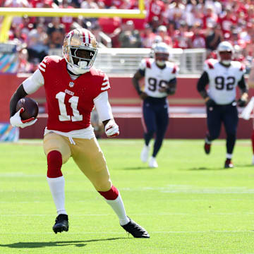 Sep 29, 2024; Santa Clara, California, USA; San Francisco 49ers wide receiver Brandon Aiyuk (11) runs with the ball past New England Patriots linebacker Jahlani Tavai (48) during the first quarter at Levi's Stadium. Mandatory Credit: Sergio Estrada-Imagn Images