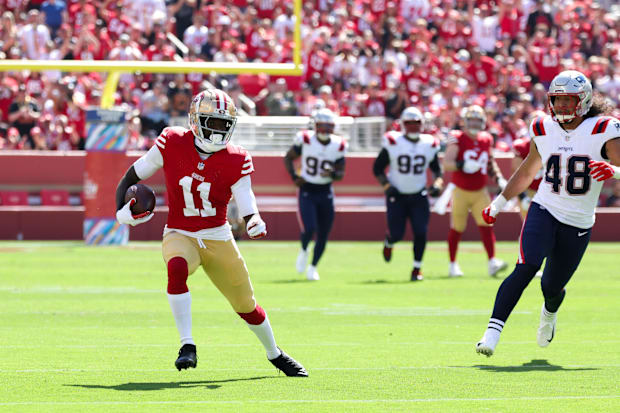 San Francisco 49ers wide receiver Brandon Aiyuk (11) runs with the ball past New England Patriots linebacker Jahlani Tavai (4