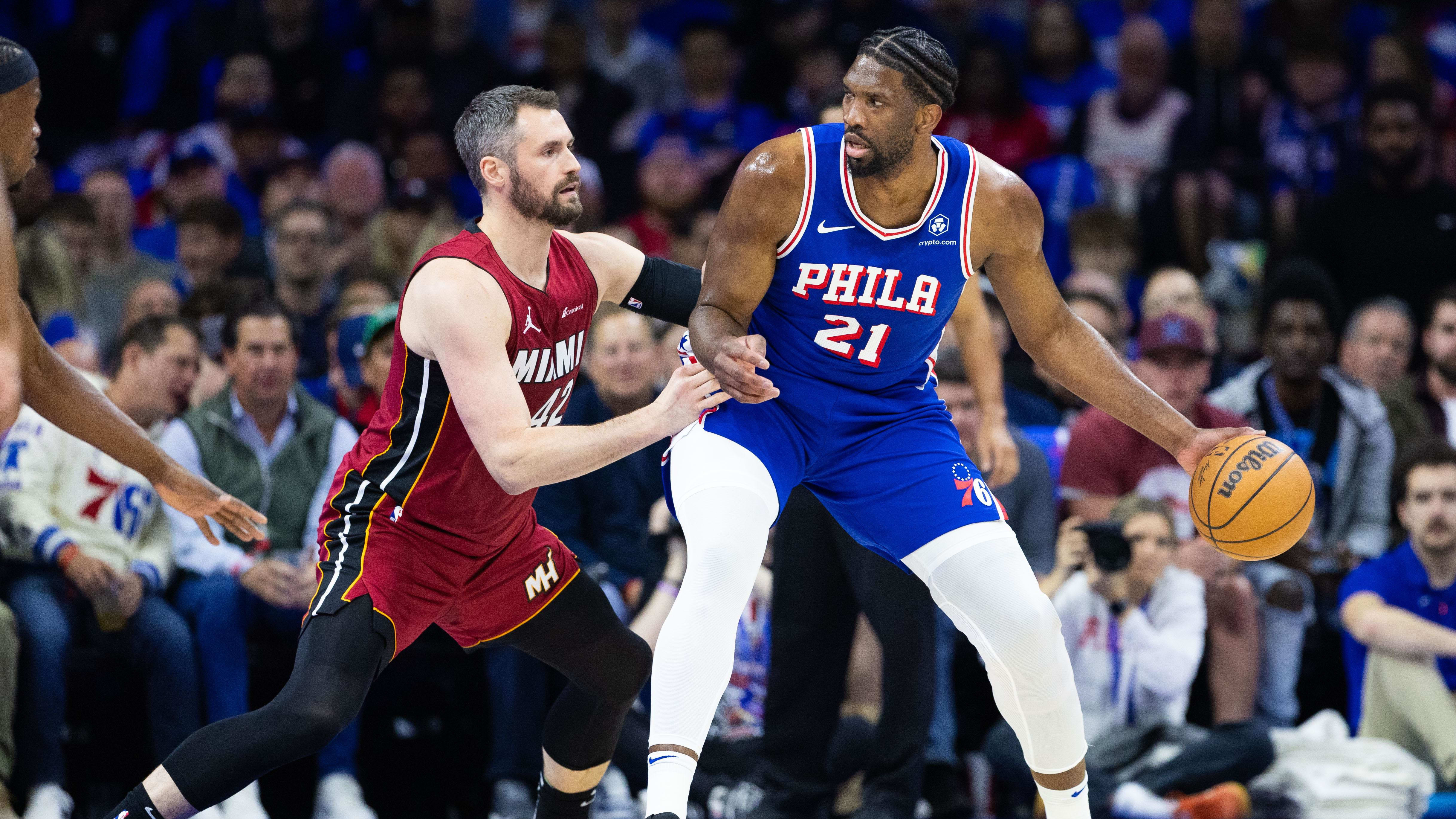 Joel Embiid dribbles the ball as Kevin Love guards him