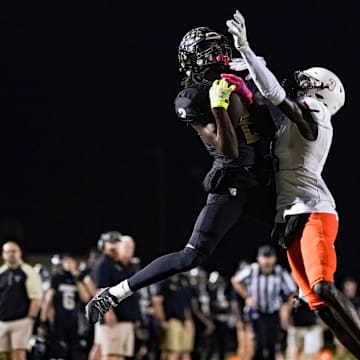 Golden Gate Titans receiver Bradley Martino (2) catches a pass while being defended by Lely Trojans defensive back Edwoun Octa (3) during the fourth quarter of a district game at Golden Gate High School in Naples on Friday, Oct. 27, 2023.