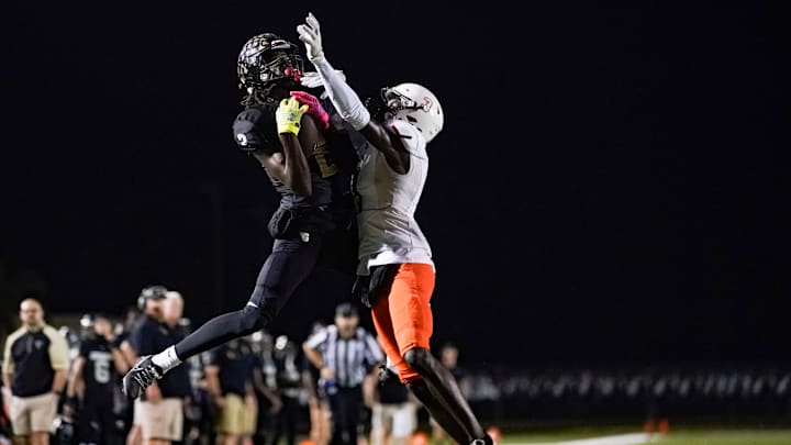 Golden Gate Titans receiver Bradley Martino (2) catches a pass while being defended by Lely Trojans defensive back Edwoun Octa (3) during the fourth quarter of a district game at Golden Gate High School in Naples on Friday, Oct. 27, 2023.