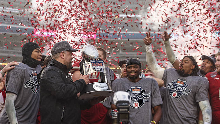 Dec 28, 2024; Bronx, NY, USA; Nebraska Cornhuskers head coach Matt Rhule holds the championship trophy as Cornhuskers players celebrate after the game against the Boston College Eagles at Yankee Stadium. Mandatory Credit: Vincent Carchietta-Imagn Images