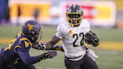 Nov 23, 2024; Morgantown, West Virginia, USA; UCF Knights running back Myles Montgomery (22) runs for extra yards against the West Virginia Mountaineers during the second quarter at Mountaineer Field at Milan Puskar Stadium. Mandatory Credit: Ben Queen-Imagn Images