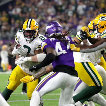 Green Bay Packers running back Josh Jacobs (8) looks for room to run against Minnesota Vikings safety Josh Metellus (44) during their football game Sunday, December 29, 2024, at U.S. Bank Stadium in Minneapolis, Minnesota.