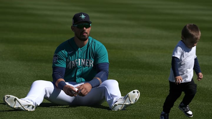 Feb 25, 2023; Peoria, Arizona, USA; Seattle Mariners catcher Jacob Nottingham warms up with his son Aiden Nottingham prior to the game against the Los Angeles Angels at Peoria Sports Complex. Mandatory Credit: Joe Camporeale-Imagn Images
