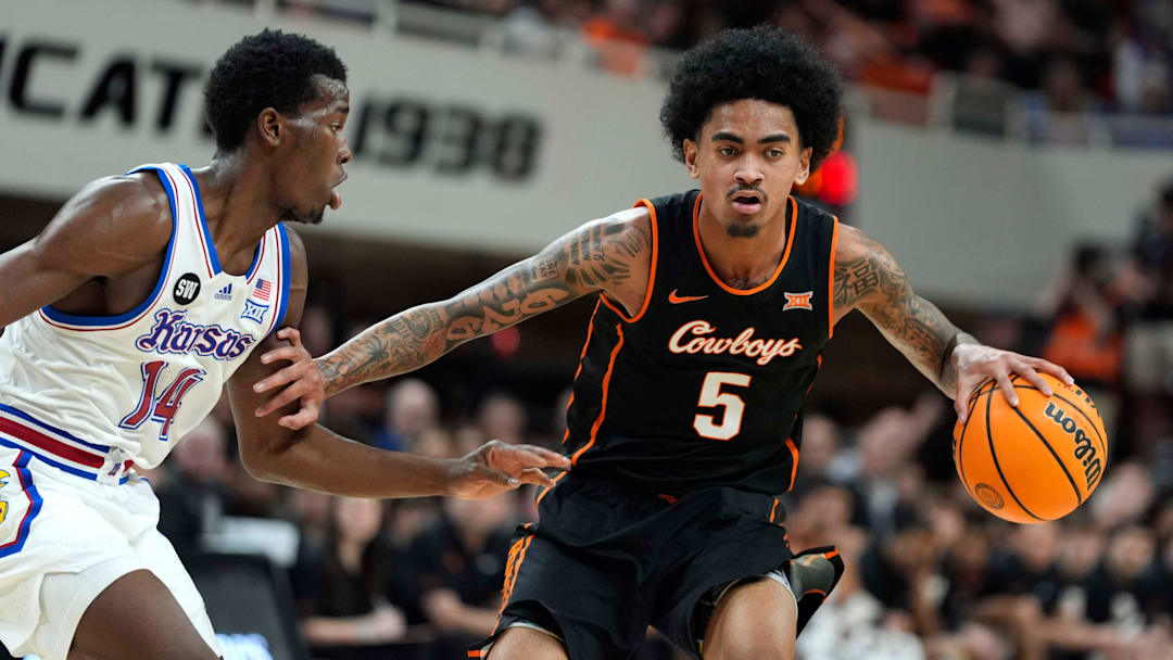 Oklahoma State Cowboys guard Vyctorius Miller (5) dribbles beside Kansas Jayhawks guard Melvin Council Jr. (14) during a men's college basketball game between the Oklahoma State Cowboys and the Kansas Jayhawks at Gallagher-Iba Arena in Stillwater, Okla., Wednesday, Feb. 18, 2026.