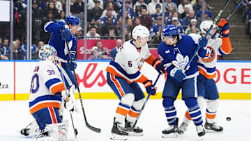 Dec 31, 2024; Toronto, Ontario, CAN; Toronto Maple Leafs left wing Nicholas Robertson (89) battles for the puck in front of the net with New York Islanders defenseman Ryan Pulock (6) during the third period at the Scotiabank Arena. Mandatory Credit: Nick Turchiaro-Imagn Images